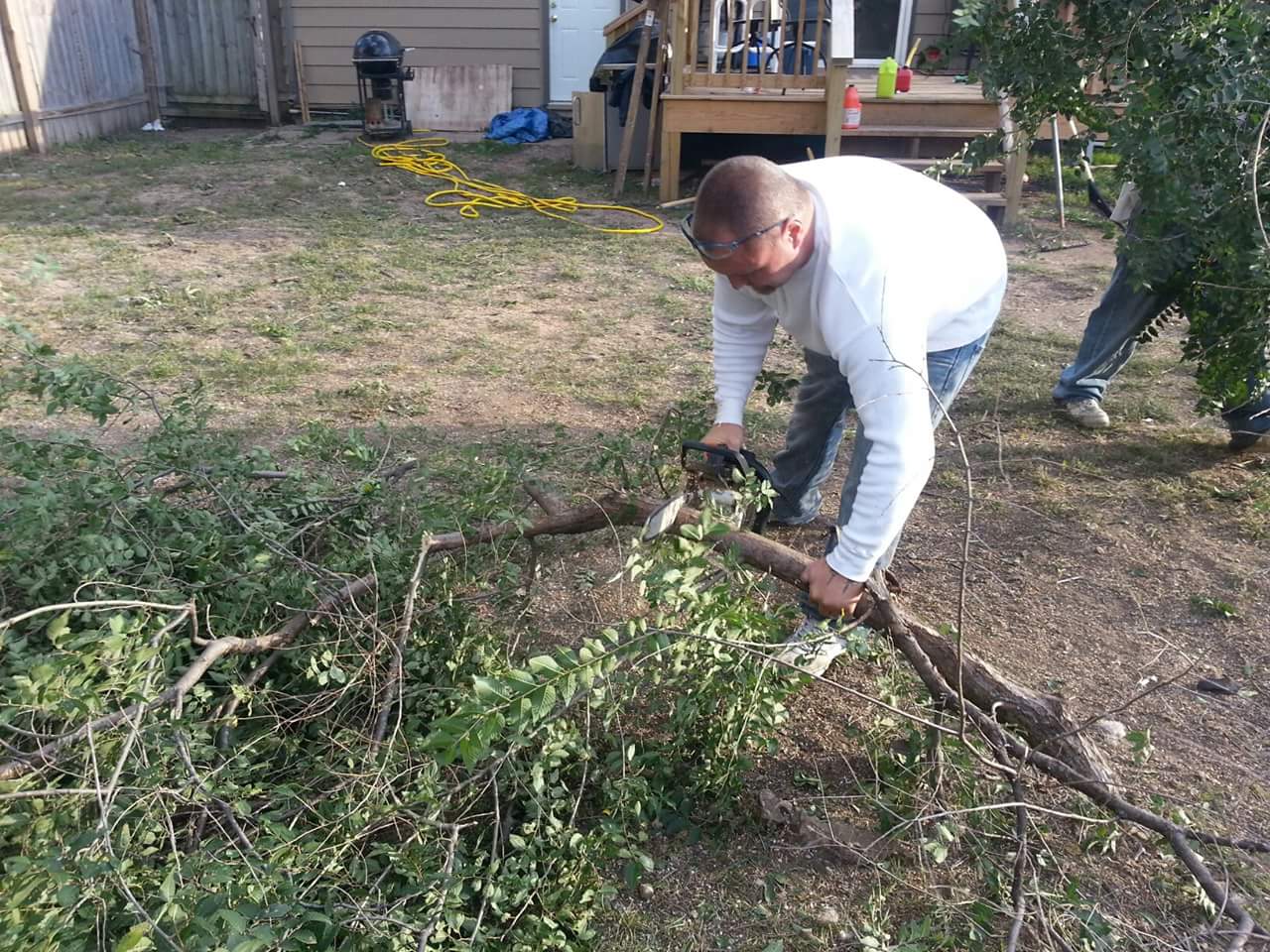 A Morning Wood crewman cutting up brush in a backyard